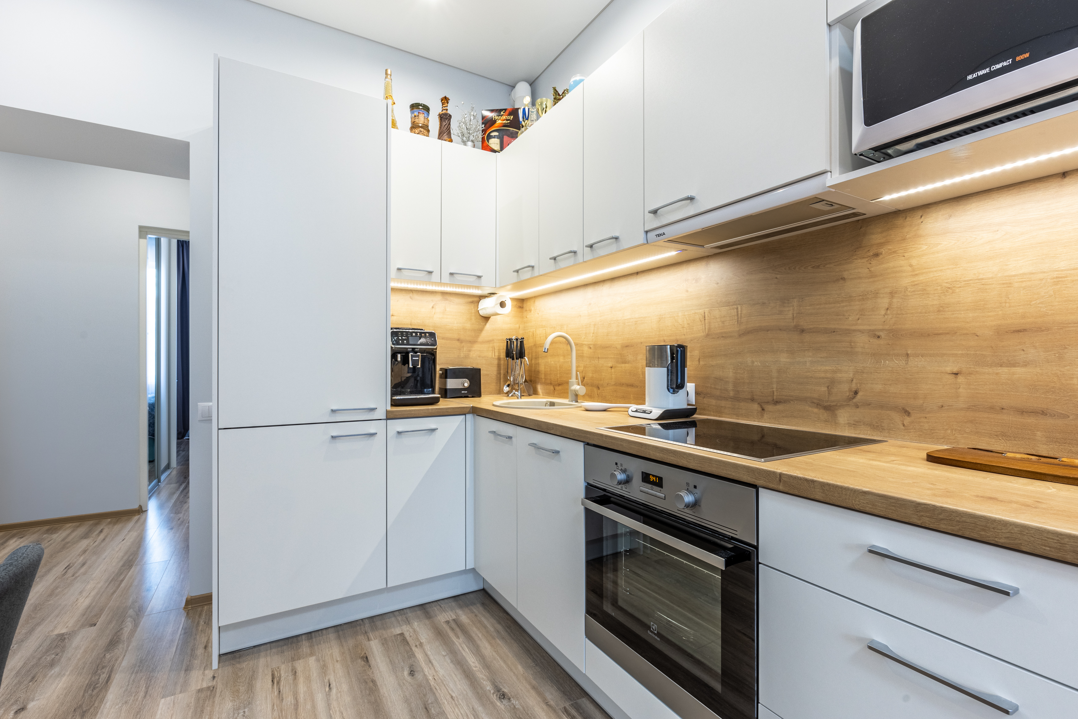 Valge köögimööbel puidust tasapinnaga, sisaldab kohvimasinat ja integreeritud ahju