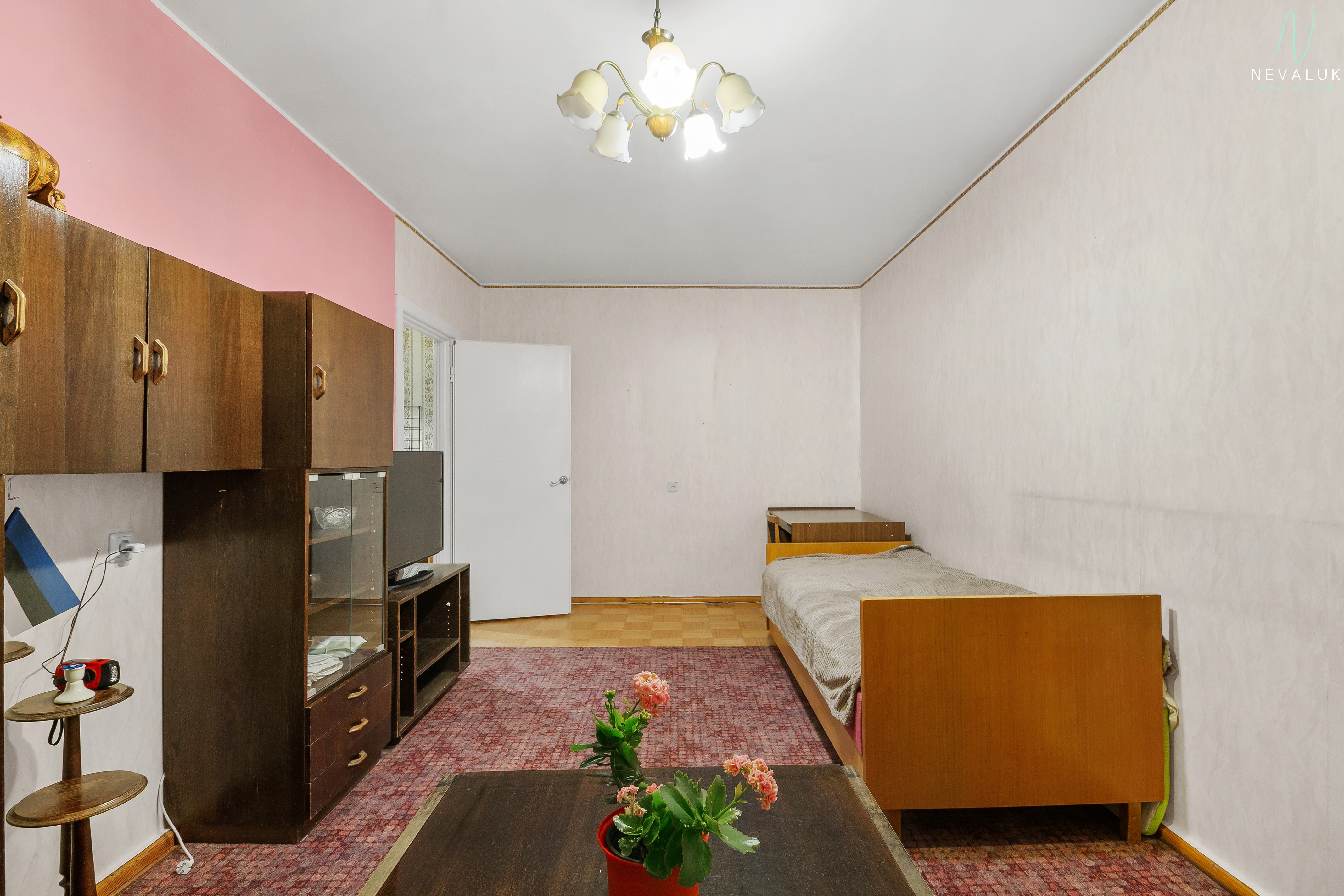 Vaade elutoale teise nurga alt, parkettpõrandal on vaip ja ruumis on palju valgust